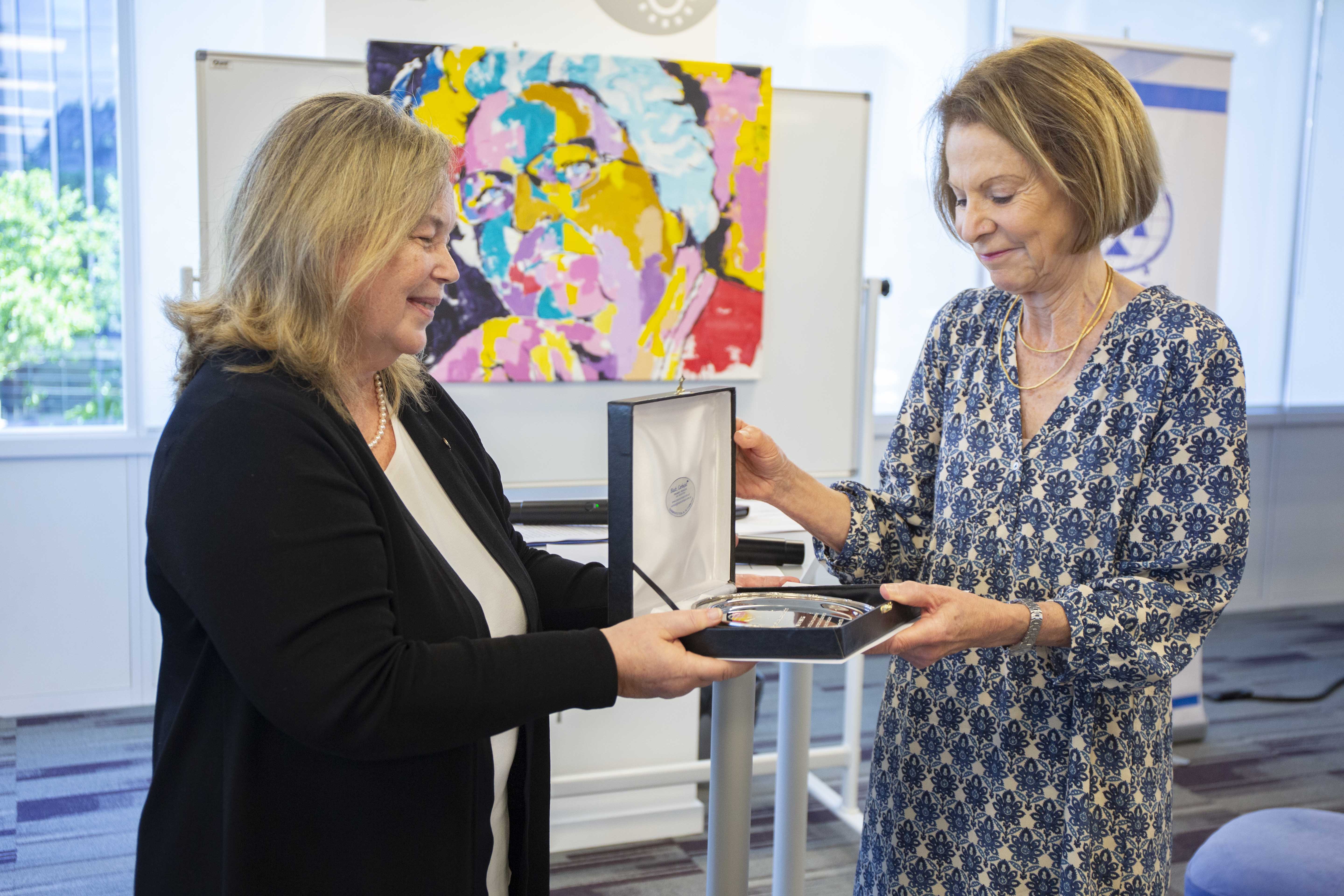 La Presidente recibe la placa que reconoce su labor de manos de la presidente de AMJA, Susana Medina.